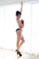 Standing in front of curtained window wearing bra and panties in high heels.jpeg